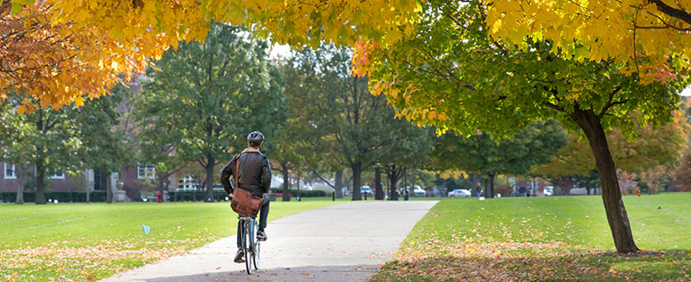 student riding bicycle in Fall on Illinois quad